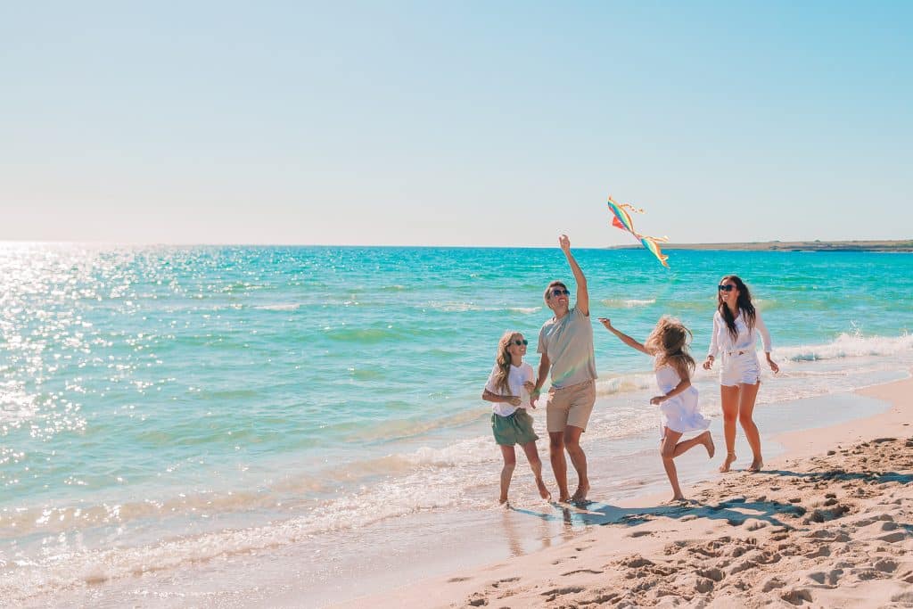 Famille jouant au cerf-volant sur une plage de Méditerranée pendant les vacances dans l’Hérault